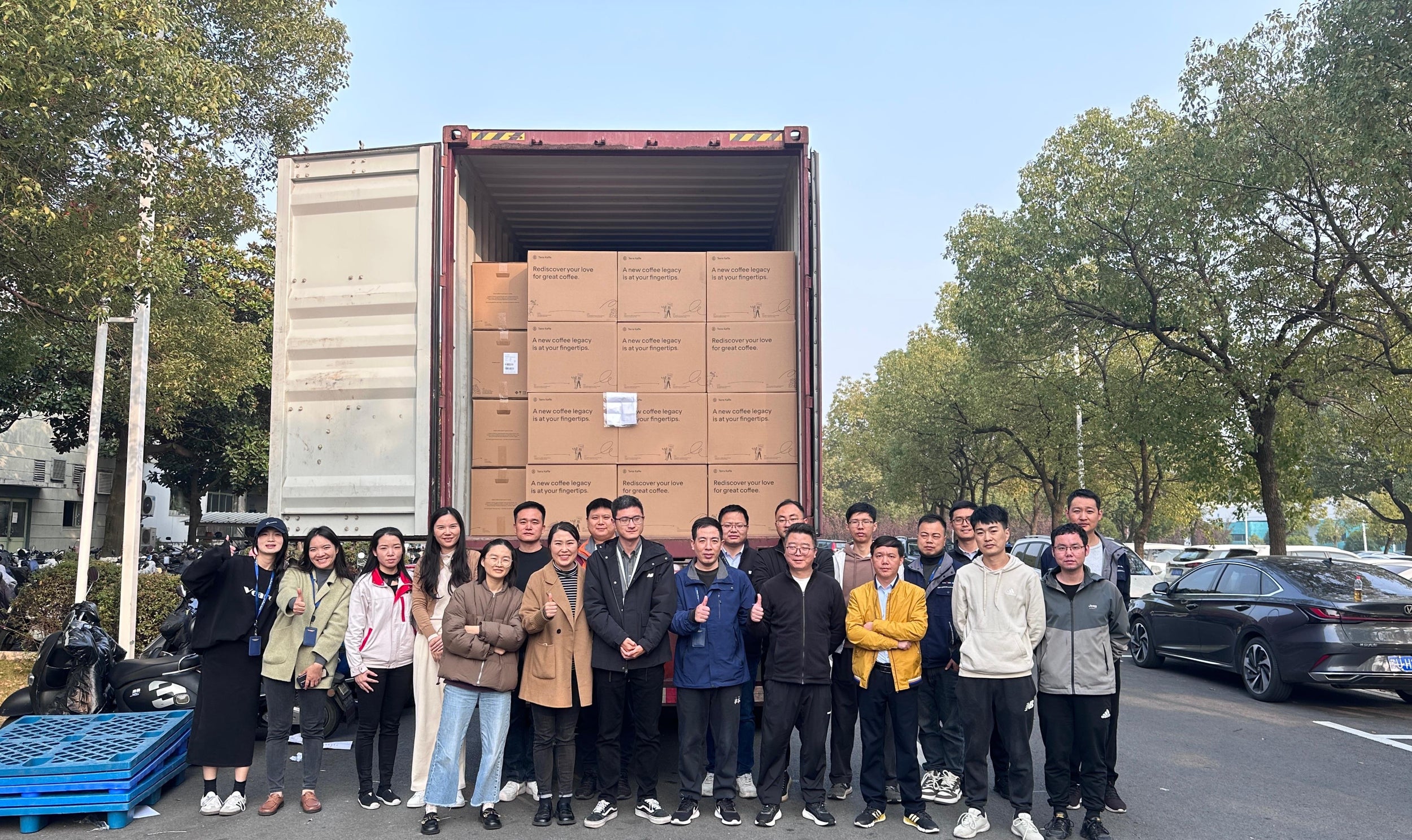 Kalerm employees stand in front of a truck filled with TK-02 machines in boxes.