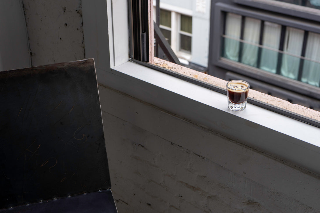 A lone espresso glass sits on an open windowsill 