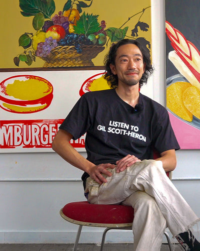 Toya Horuchi sitting on a chair inside his art studio