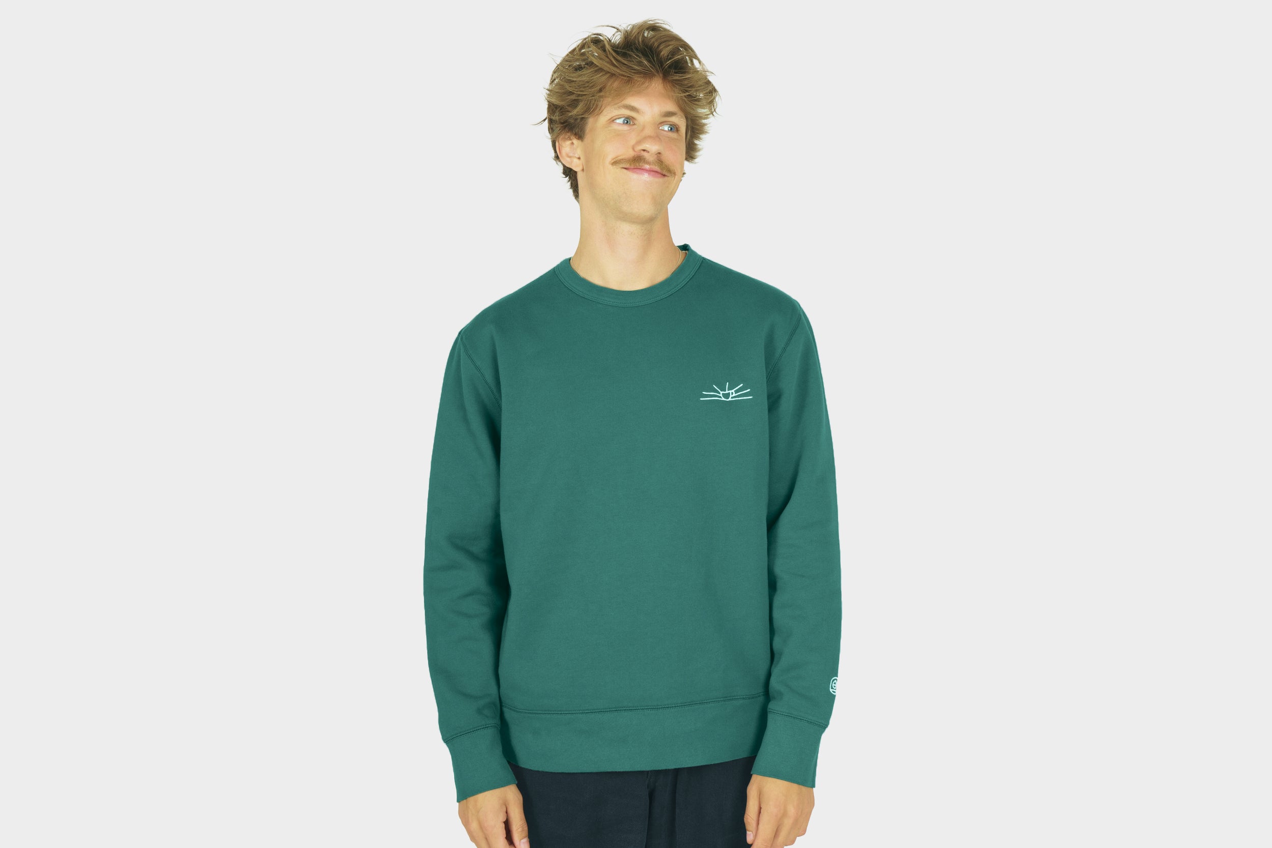 Terra Kaffe | Man wearing a dark green sweater with a small sunshine design in the top right corner