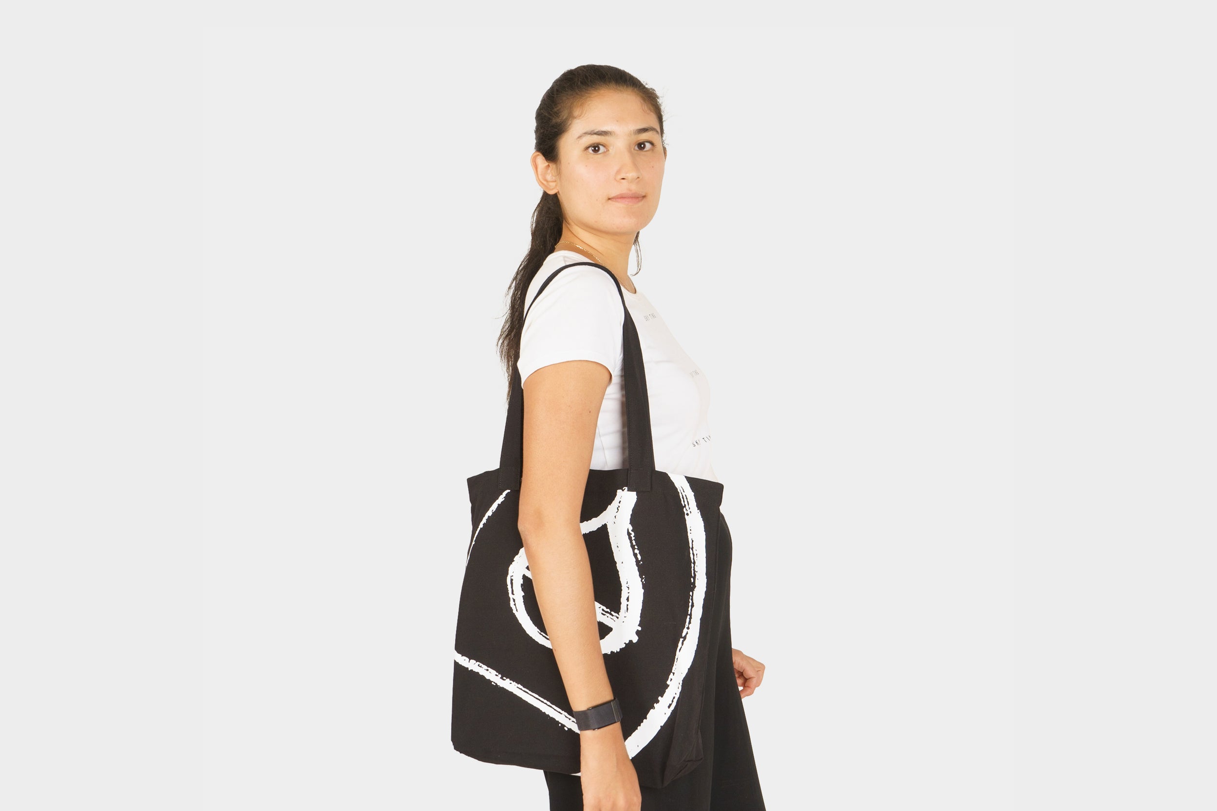 Terra Kaffe | Woman wearing black tote bag with large white Terra Kaffe logo painted on