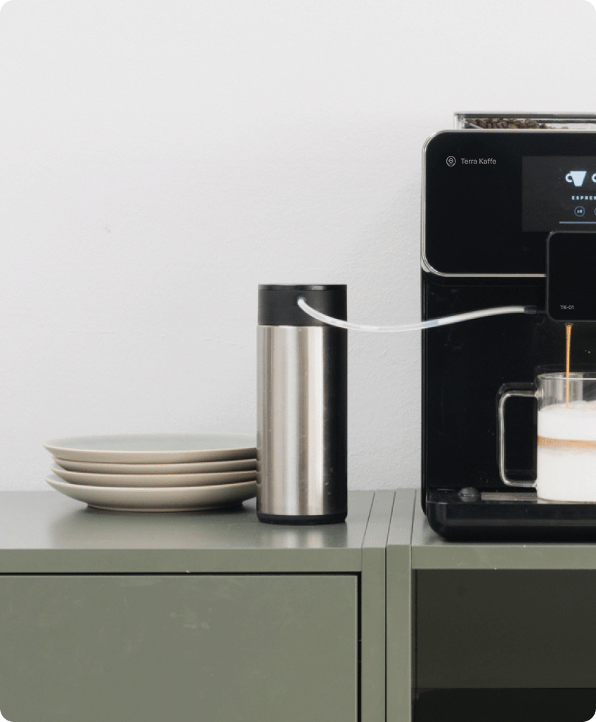 Terra Kaffe | Black TK-01 on a green counter with Milk Carafe